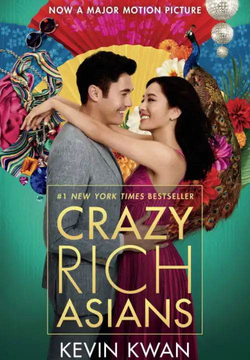 Book Cover of Crazy Rich Asians. An asian man wearing a grey suit and woman wearing a bright pink dress stand facing each other. The woman has her arms over the mans shoulders and he has his hands on her waist. They look into each others eyes smiling, showing teeth. Behind their heads are a number of colourful fans. A peacock stands next to one fan. a silver ball chandelier hangs above it. Placed over the other fans are a striped silk scarf, some sunglasses and jewels.