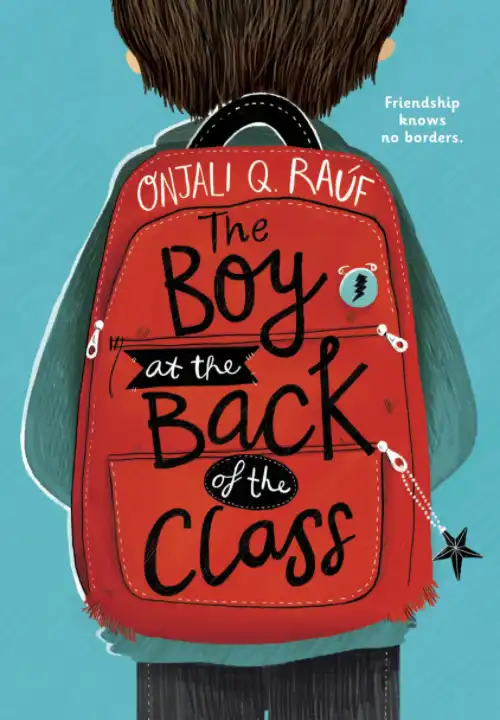 Book Cover of The Boy at the Back of the Class. A drawing of a young boy facing away from us wearing a red backpack. The boy has short brown hair and is wearing a green jumper and black trousers. On the zip of his bag is a 5 pointed star keychain. A badge is pinned to the top pocket of the backpack